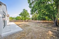 058 - 2990 Limestone Road - Spacious backyard with a white-tiled patio, wooden fencing, and large shade trees