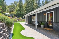 003 - 3165 Lucas Drive - Covered patio with seating area, brick pavers, and landscaped hillside views.