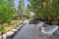 032 - 3165 Lucas Drive - Elevated brick patio with  seating,  terraced landscaping, and a pathway leading to a garden area.