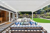 030 - 3165 Lucas Drive - Covered backyard patio, outdoor dining area, and terraced landscaping with stone steps and artificial turf.