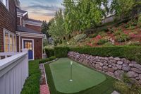 48 - 231 Sundown Terrace - A backyard putting green bordered by stone walls and manicured hedges.