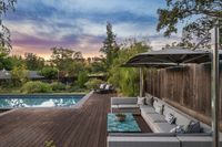 44 - 840 Broadmoor Court - Poolside lounge with sectional seating, a turquoise coffee table, and an umbrella, set against a beautiful sunset backdrop.