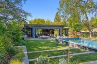 45 - 840 Broadmoor Court - Backyard of the house with a manicured lawn, swimming pool, and patio seating surrounded by greenery.