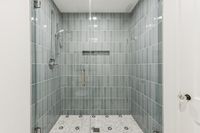 33 _ 1089 Rahara  Drive _ Shower area with tiled walls, glass door, and built-in shelf