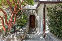 45 _ 1089 Rahara  Drive _ Outdoor entry with stone walls, wooden door, and surrounding plants