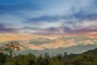 43 _ 21 Nemea Lane _ Panoramic view of rolling hills and mountain ridges beneath a colorful sky at sunset