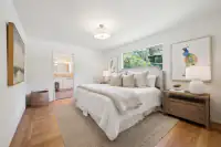 19 - 3435 Black Hawk Road - Primary bedroom with ensuite bathroom, hardwood floors, and large window overlooking the garden.