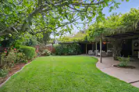 3 _ 808 Rosedale - Backyard with landscaped lawn, mature trees, garden beds, covered patio, and outdoor seating area