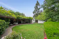 12 _ 808 Rosedale - Backyard with lawn, covered patio, garden beds, mature trees, and a detached structure