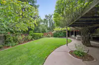 24 _ 808 Rosedale - Lush backyard with mature landscaping, a spacious lawn, and covered patio seating