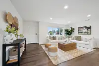 3 _ 866 Wilmore Ave _ Living room with two sofas, wicker coffee table, woven ottomans, and console table