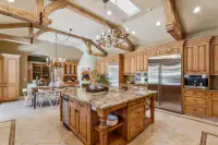 16 _ 24 Cosso Court _ Kitchen with a wooden dining table, white chairs, wooden cabinetry, and exposed ceiling beams