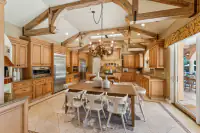 17 _ 24 Cosso Court _ Kitchen with a wooden dining table, white chairs, wooden cabinetry, and exposed ceiling beams