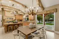18 _ 24 Cosso Court _ Kitchen with a granite island, wooden cabinetry, dining table, and sliding glass doors overlooking the backyard