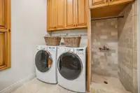 45 _ 24 Cosso Court _ Laundry area with front-loading washer and dryer beside tiled shower alcove